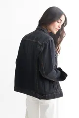 Campera de jean celeste con cuello clásico, cierre frontal con botones metálicos negros, bolsillos con solapa abotonada en el pecho y mangas largas con puños abotonados.
