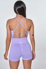 Conjunto deportivo de dos piezas en color lila, compuesto por un top de breteles finos con diseño acanalado y logo estampado, y un short de tiro alto de calce ajustado.