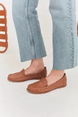 Mocasines de cuero color dorado con acabado texturizado, diseño clásico de punta redondeada y costuras visibles en el empeine. Cuentan con suela plana y flexible.