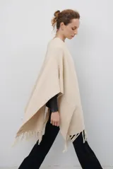 Ruana de tejido de punto en color negro, con diseño de cuello alto y terminaciones con flecos en los bordes.