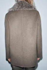 Chaqueta de corte recto confeccionada en mezcla de lana, color marrón topo. Presenta un cuello de solapa amplio con aplicación de pelo sintético desmontable, cierre frontal cruzado con botones y bolsillos laterales con solapa.