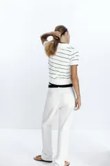 Jersey de punto blanco con rayas horizontales negras, cuello polo blanco y manga corta. Presenta una botonera frontal de tres botones negros.