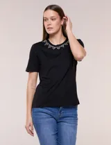 Remera de algodón de calce recto y color negro, con mangas cortas y cuello redondo adornado con una aplicación de piedras brillantes a modo de collar.