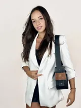 Bolso baguette de cuero negro con asa reversible y logo de la marca en etiqueta de cuero marrón.