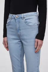 Pantalon jean de corte flare, tiro medio, con ruedo desflecado y cierre frontal con botón y cremallera.