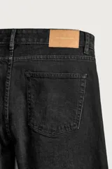 Jeans regular fit de mezclilla negra con efecto lavado, corte recto y tiro medio. Cuenta con diseño de cinco bolsillos y cierre frontal con cremallera y botón.