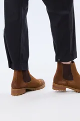 Pantalón de gabardina marrón, de corte recto con pinza en el bajo y detalles de botones en los tobillos.