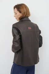 Blazer de cuero color marrón, con corte entallado, cuello con solapas, cierre frontal con botones y bolsillos laterales con solapa.