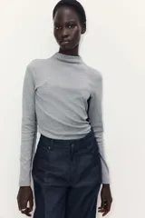 Top de punto suave con cuello alto y mangas largas, de corte entallado.