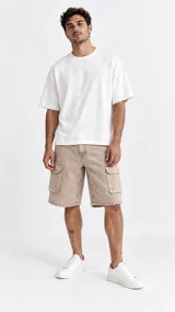 Bermuda cargo estilo baggy de jean color beige con efecto pigmentado, corte holgado y bolsillos laterales con solapa.
