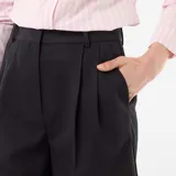 Bermuda de tiro alto color negro, con diseño de pinzas en el frente, corte recto y largo por encima de las rodillas.