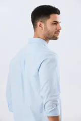 Camisa de lino de manga larga en color beige, con cuello camisero, cierre frontal de botones y un bolsillo ojal en el pecho.