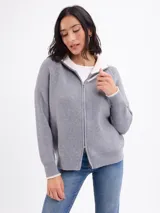 Campera de tejido de punto en color gris, con cierre frontal completo y cuello alto. Presenta un diseño de canalé vertical y puños con detalle en contraste.
