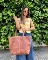 Bolso tipo tote bag color suela, confeccionado artesanalmente en cuero, con costuras visibles decorativas en los bordes y asas de hombro.
