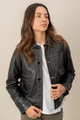 Campera de cuero marrón, con cuello camisero, cierre frontal con botones metálicos y bolsillos frontales.