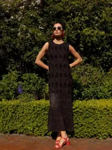 Vestido midi de tejido de punto con diseño de rombos y textura de red con hilos de lurex. Presenta un corte recto, cuello redondo, sin mangas y tajos laterales en el ruedo.