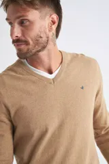 Sweater de tejido de punto color beige, con escote en V, mangas largas y puños y dobladillo acanalados. Presenta un pequeño logo bordado en el pecho.