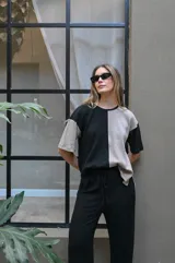 Remera de tejido de punto, manga corta, con diseño bicolor en negro y beige. La prenda es de corte holgado y presenta un ligero acanalado vertical.