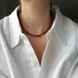 Collar tipo gargantilla elaborado con escallas de ámbar natural en tonos rojizos y marrones, con cierre y detalles metálicos con baño de oro.