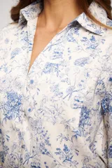 Camisa de manga larga color crema con estampado floral en tonos azules, cuello camisero y escote en V profundo.