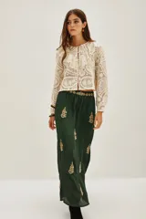 Vestido largo de satén color verde oscuro, con mangas tres cuartos terminadas en volados. Presenta un diseño con bordados dorados detallados en el pecho y cuello, además de motivos florales bordados dispersos a lo largo de la falda. Incluye un cinturón fino con aplicaciones brillantes.