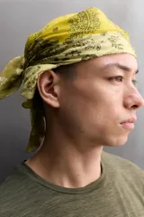 Bandana cuadrada confeccionada en tejido ligero de mezcla de ramio y algodón, con diseño de patchwork que combina paneles con estampados florales y paisley en tonos amarillo, mostaza y verde militar.
