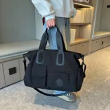 Bolso deportivo multifunción color negro, con diseño liso, compartimento principal con cierre, bolsillo frontal con solapa y bolsillo frontal con cierre. Cuenta con doble asa de mano y correa de hombro ajustable y extraíble. Incluye detalle de logo circular en la parte inferior.