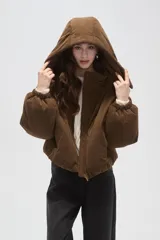 Campera puffer de color beige con cuello alto, capucha desmontable, cierre frontal y bolsillos laterales. Diseño de corte holgado con puños elásticos.