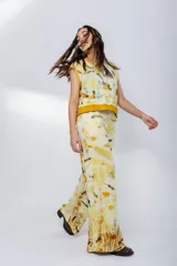 Pantalón de pierna ancha con estampado de hojas en tonos amarillos y marrones, cintura elastizada y bolsillos laterales.