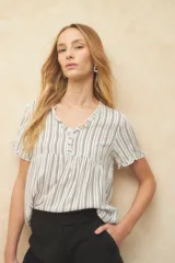 Blusa blanca con finas rayas verticales negras, de manga corta con volados y escote en V con pequeños botones y detalle de volado en el borde.