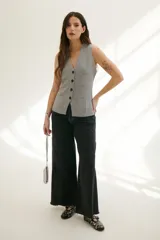 Chaleco tejido de punto en color beige, con escote en V, cierre frontal con botones oscuros y bolsillos frontales decorativos.