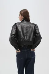 Campera de eco-cuero negro con cuello alto, cierre frontal, bolsillos con solapa en el pecho y puños y ruedo elásticos.