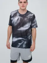 Remera deportiva Umbro modelo Niso, de manga corta y cuello redondo, con estampado abstracto en tonos negro y gris, y logo de la marca impreso en el pecho.