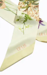 Pañuelo cuadrado de material sintético con estampado floral en tonos crema, verde y violeta, con bordes enmarcados y acabado fino.