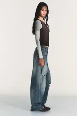 Camiseta de manga larga con diseño de capas superpuestas que crea un efecto triple. Presenta cuello redondo, corte ajustado y combinación de colores en tonos blanco, gris y negro.