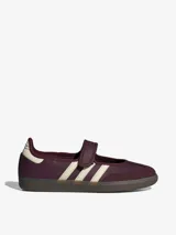 Zapatillas Adidas modelo Samba Jane, color bordó con detalles en blanco. Presentan un diseño tipo Mary Jane con cierre de velcro en el empeine, manteniendo la estética clásica de las Samba con las tres tiras laterales y suela de goma.