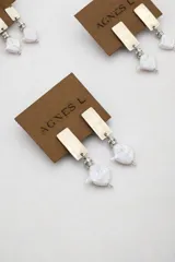 Aros colgantes con diseño de placa rectangular metálica plateada, unidos mediante un pequeño engarce con strass a una perla barroca irregular.