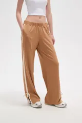 Pantalon deportivo de corte recto y tiro medio, color beige oscuro. Presenta una banda lateral en tono crema y aberturas ajustables con cordones en los tobillos. Cuenta con cintura elástica.