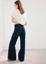 Jeans de denim azul oscuro con corte wide leg, tiro medio y botamanga ancha.