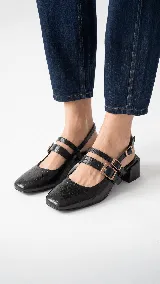 Zapato destalonado de cuero negro con textura símil cocodrilo, punta cuadrada, doble tira frontal con hebillas metálicas doradas y taco ancho bajo.