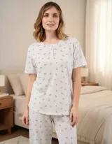 Pijama capri de algodón en color gris melange con delicado estampado floreado. Consta de una remera de manga corta con escote redondo y cierre frontal de botones, y un pantalón capri con elástico en la cintura.