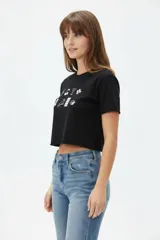 Remera cropped de algodón negra con cuello a la base, mangas cortas y estampado frontal de cerezas con la palabra "HELLO".