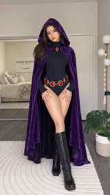 Disfraz de Raven que incluye body negro, capa con capucha de terciopelo morado, cinturón con gemas rojas y broche decorativo.