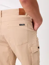 Bermuda cargo de gabardina color beige, con bolsillos laterales con fuelle en las piernas, bolsillos delanteros tipo ojal y traseros. Cuenta con presillas para cinto y cierre frontal con botón y cierre.