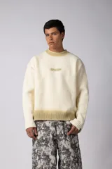 Sweater de punto acanalado con diseño degradado de negro a gris en el cuello y el ruedo. Presenta un corte regular y un pequeño bordado central en el pecho.