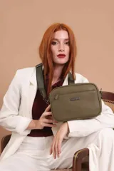 Bandolera de diseño rectangular con textura granulada, color verde oliva. Cuenta con tres compartimentos principales con cierre, un bolsillo frontal adicional y correa ancha ajustable de tela en tono a juego.