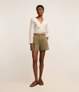Short regular de talle alto confeccionado en sarga de color marrón, con trabillas para cinturón, cierre con botón y cremallera, bolsillos delanteros y traseros, y pespuntes en contraste.