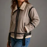 Campera gamulán tipo aviadora para mujer, color marrón claro con interior y detalles de corderito sintético blanco, ribetes y correas en cuero sintético negro, cierre frontal y bolsillos con cierre.