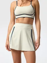 Skort deportivo color beige con detalles de líneas azul marino en los laterales y short interior integrado.