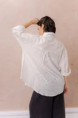 Camisa lila oversize de algodón con bordado floral calado tipo broderie, cuello camisero, manga larga y abotonadura frontal.